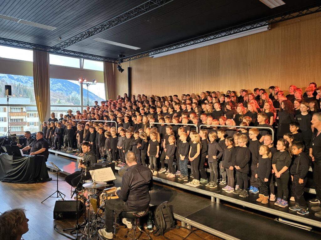 Tuttas partiziuns dalla scola da Flem, naven dalla scoletta tochen il scalem superiur, inclus il persunal d'instrucziun, meisa da miezgi e pedel, contan ensemen. Davon la band ad hoc Rolf Caflisch, Vito Cadonau, Christian Müller e Clau Maissen. La dirigenta Flavia Walder ei buca da veser silla foto.