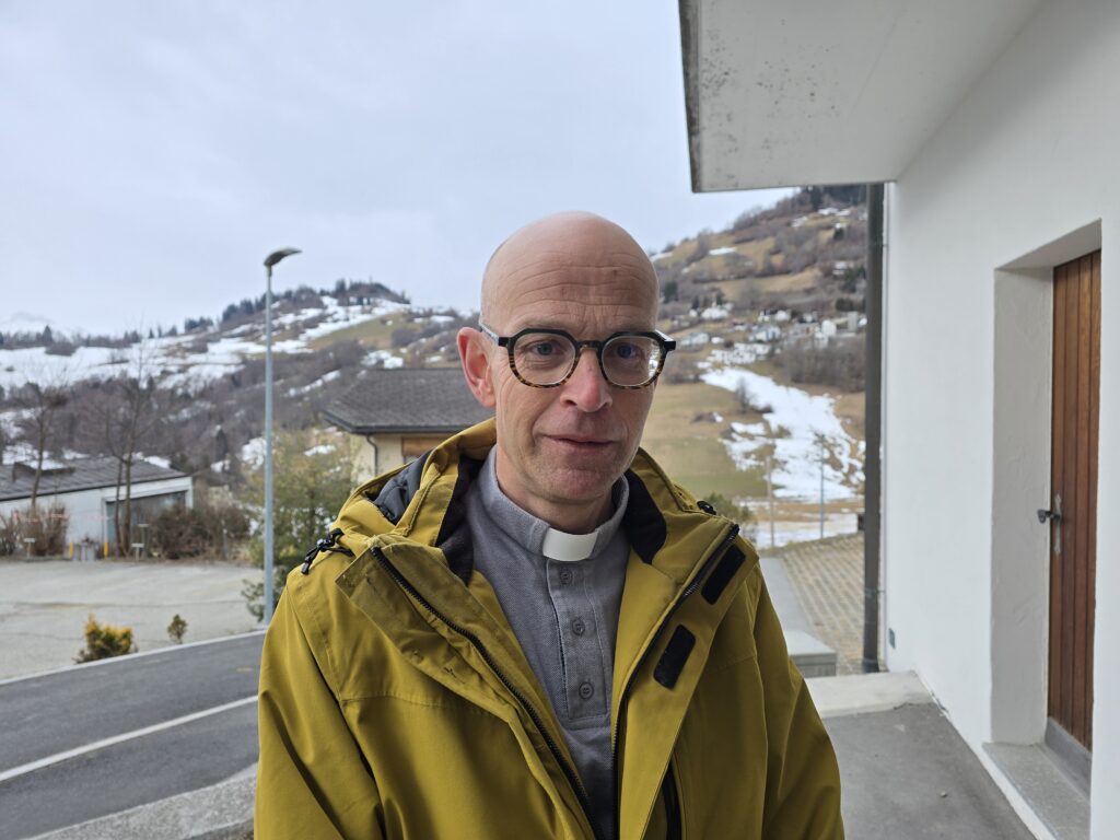 Sur Patrik porta il collar sco segn d'identificaziun dil plevon catolic.