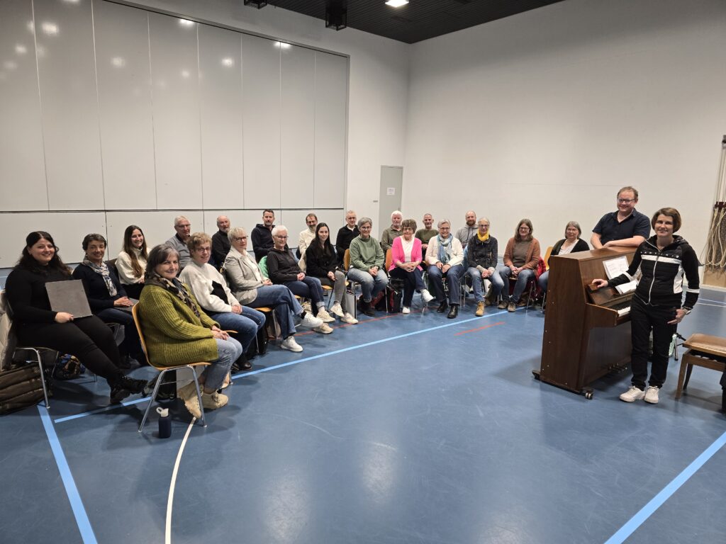 Il Chor mischedau da Schluein cun ses 22 cantaduras e cantadurs, dretg ils co-dirigents Carla Brunold e Curdin Caduff.